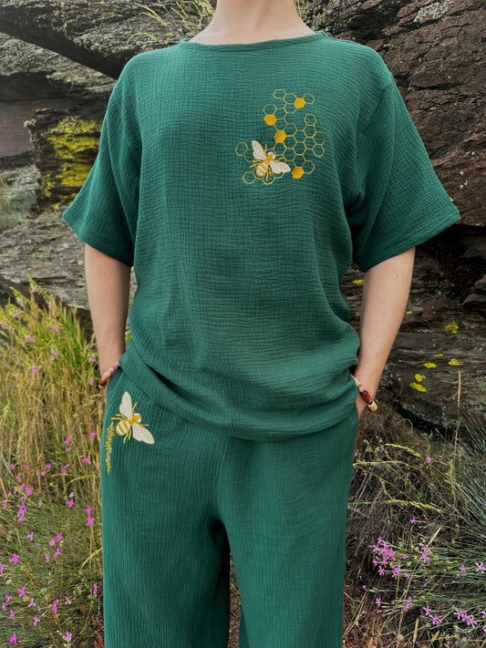 Person wearing a green outfit with floral embroidery in a natural setting