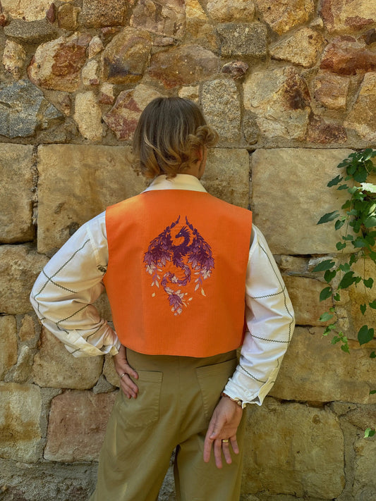 Person wearing an orange vest with a purple design against a stone wall.