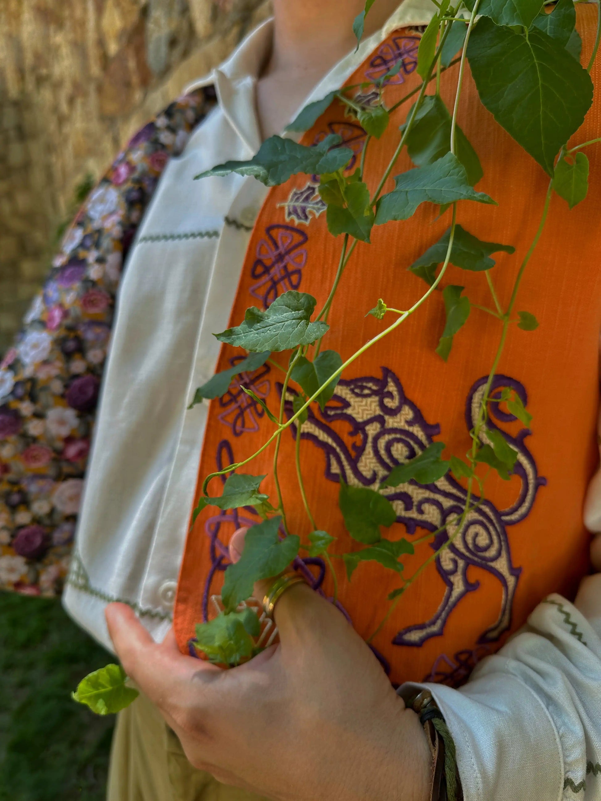 Person holding a plant with an orange bag featuring a tiger design in the background