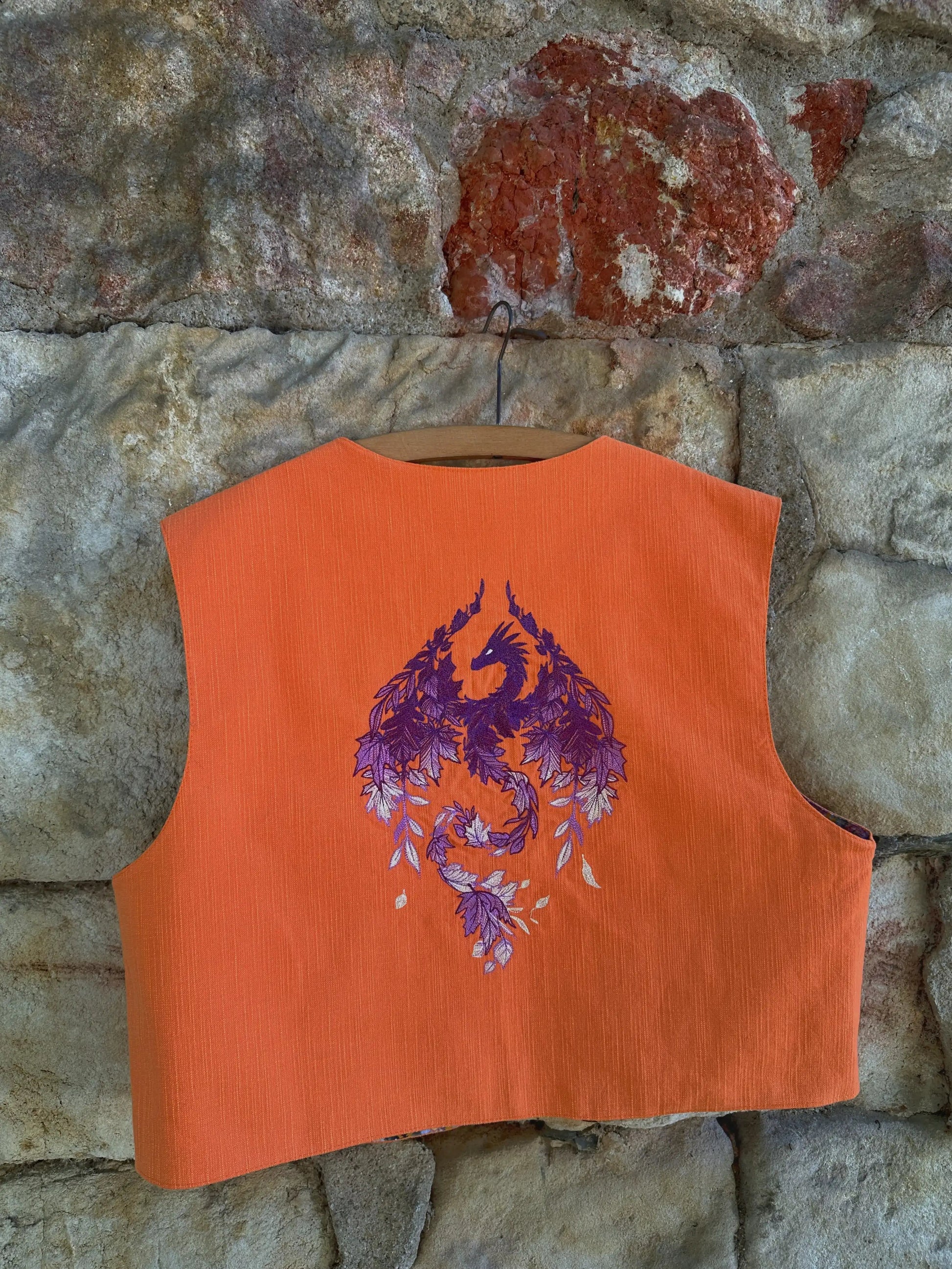 Orange vest with purple dragon design against a stone wall background