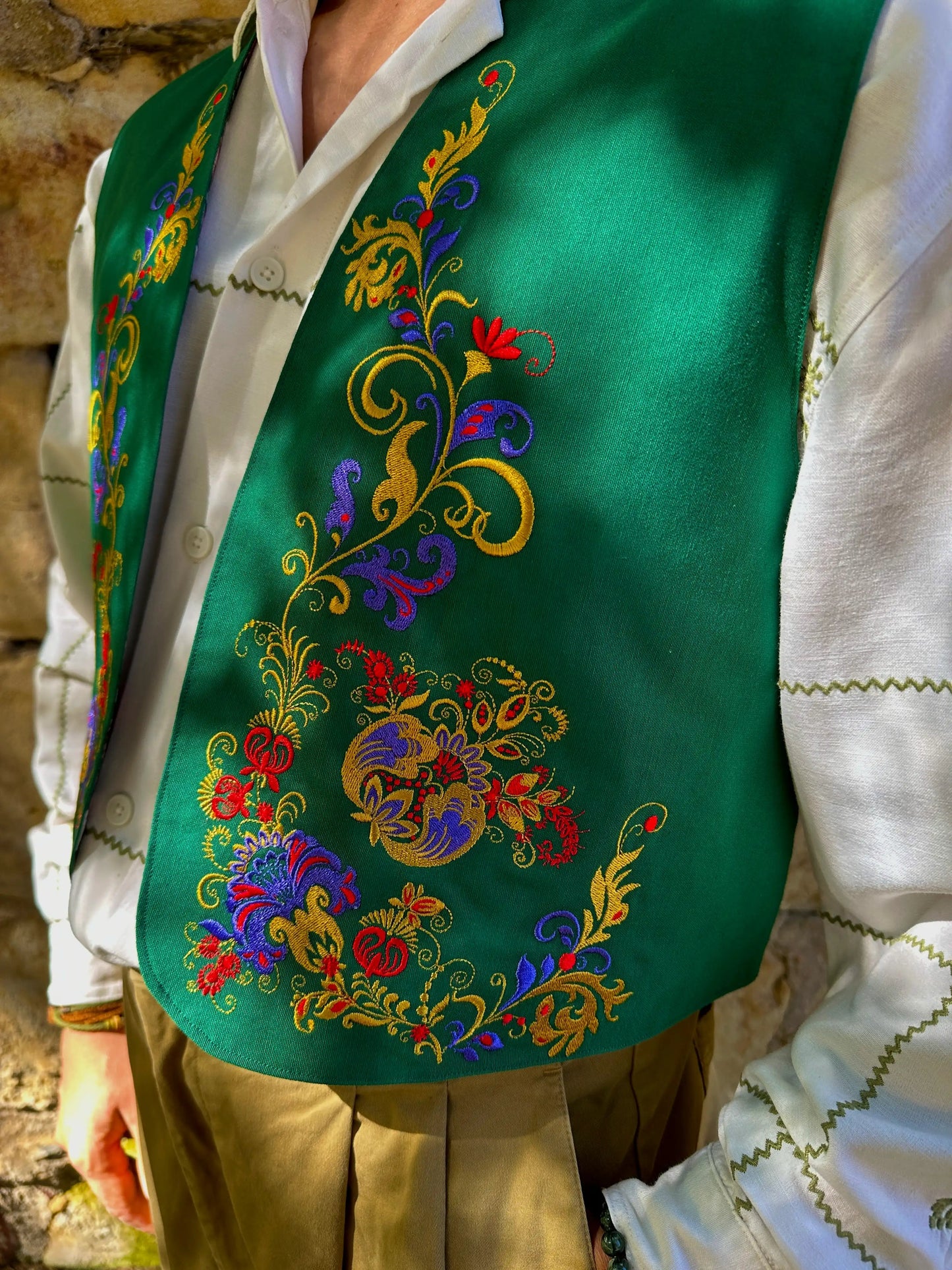 Green embroidered vest over a white shirt with a rustic background