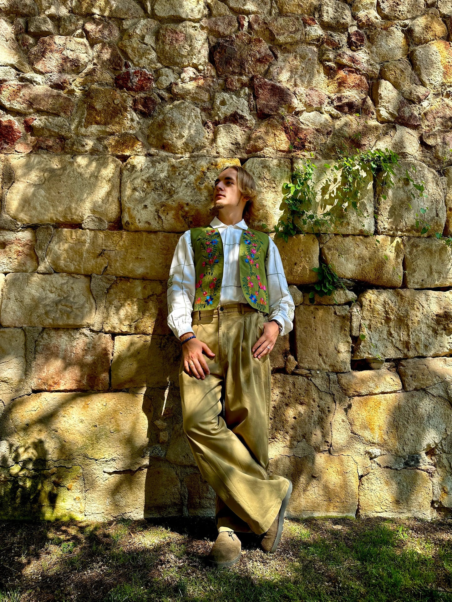 Person in historical attire standing against a stone wall