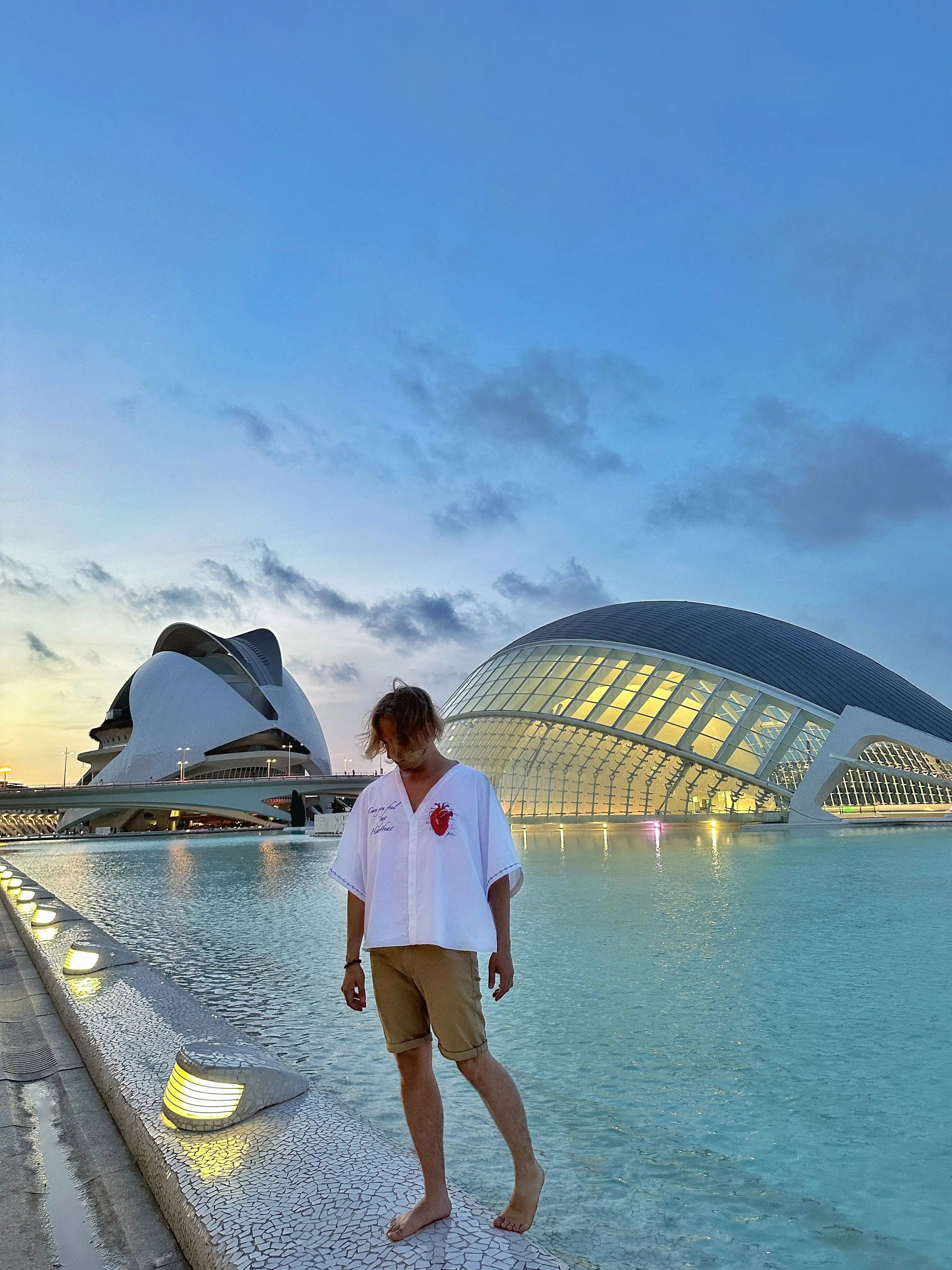 Person standing by a pool with futuristic architecture in the background