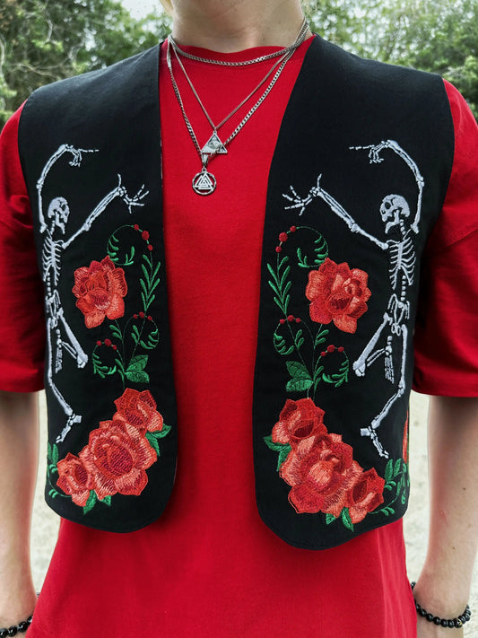 Person wearing a red shirt with a black vest featuring skeleton and rose designs.