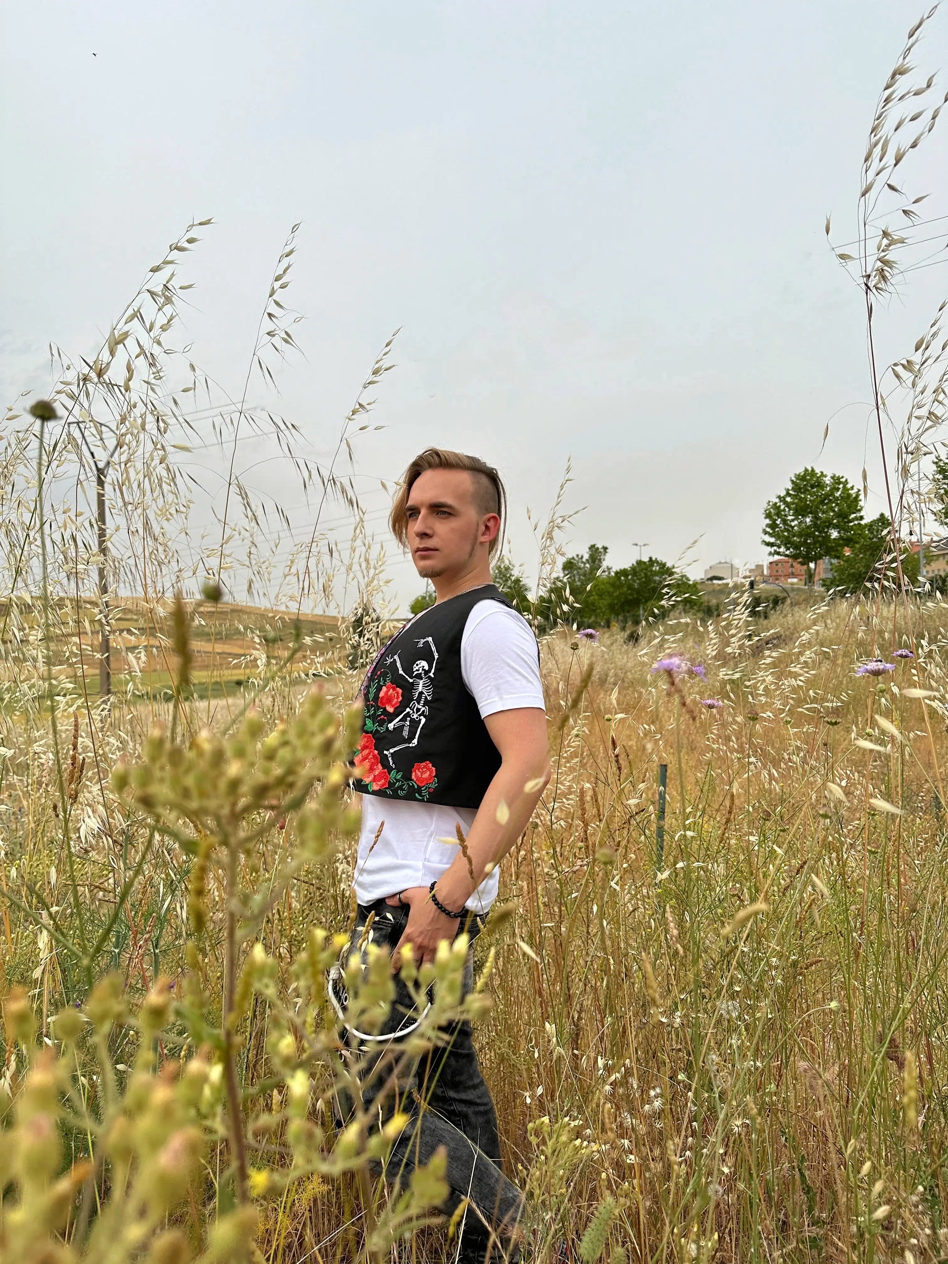 Person standing in a field of tall grass and wildflowers
