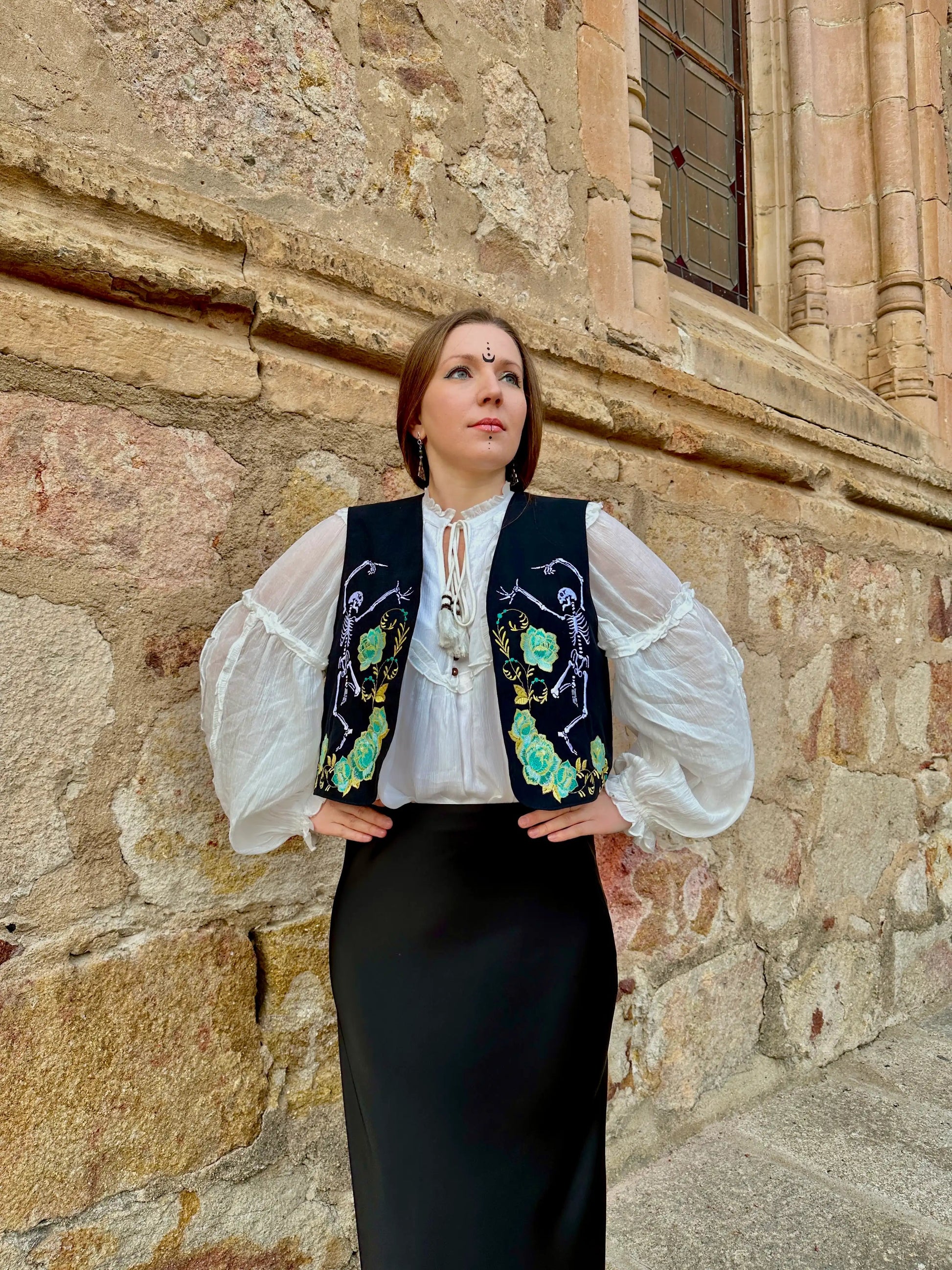 Woman in traditional outfit standing against a stone wall