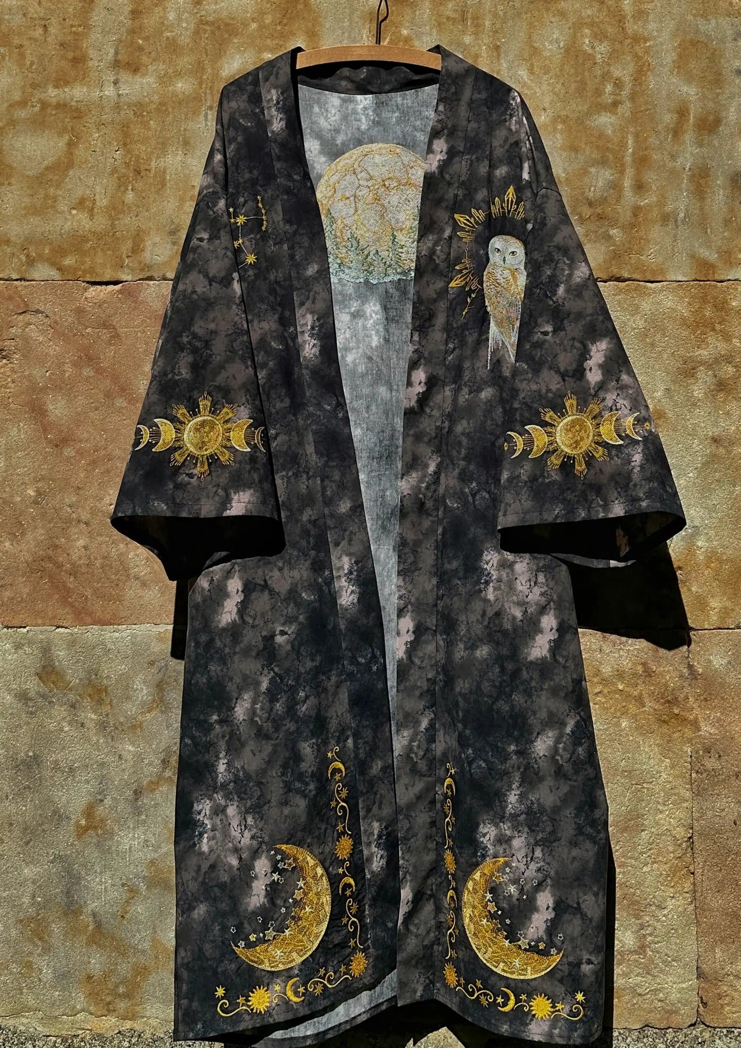 Dark robe with gold celestial designs on a stone wall background
