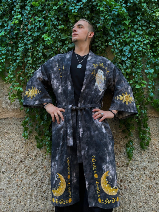 Person wearing a dark robe with yellow patterns against a green ivy-covered wall.