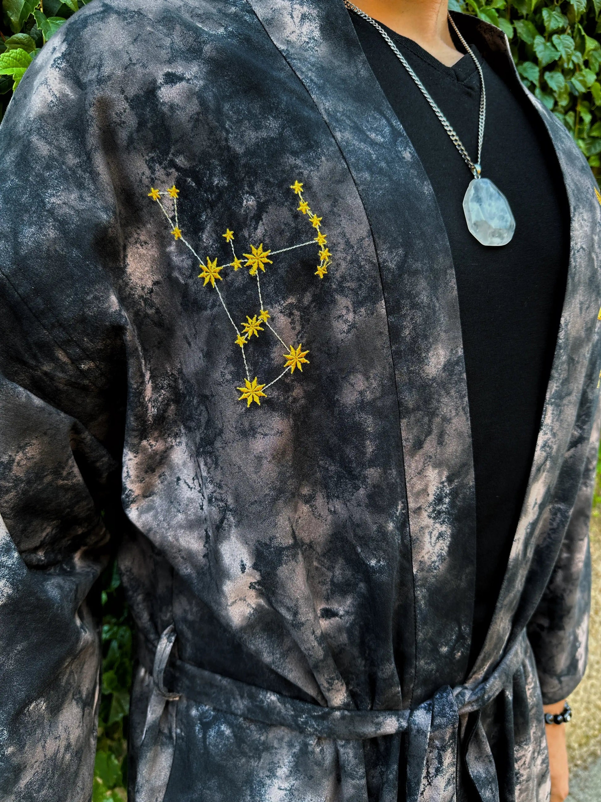 Person wearing a dark, tie-dye jacket with a star constellation design on the chest.