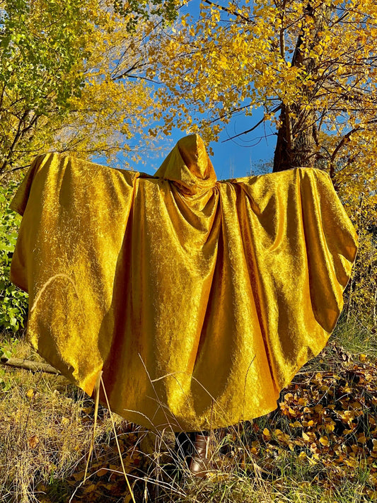 Yellow hooded cloak draped over a person in a forest with autumn foliage.