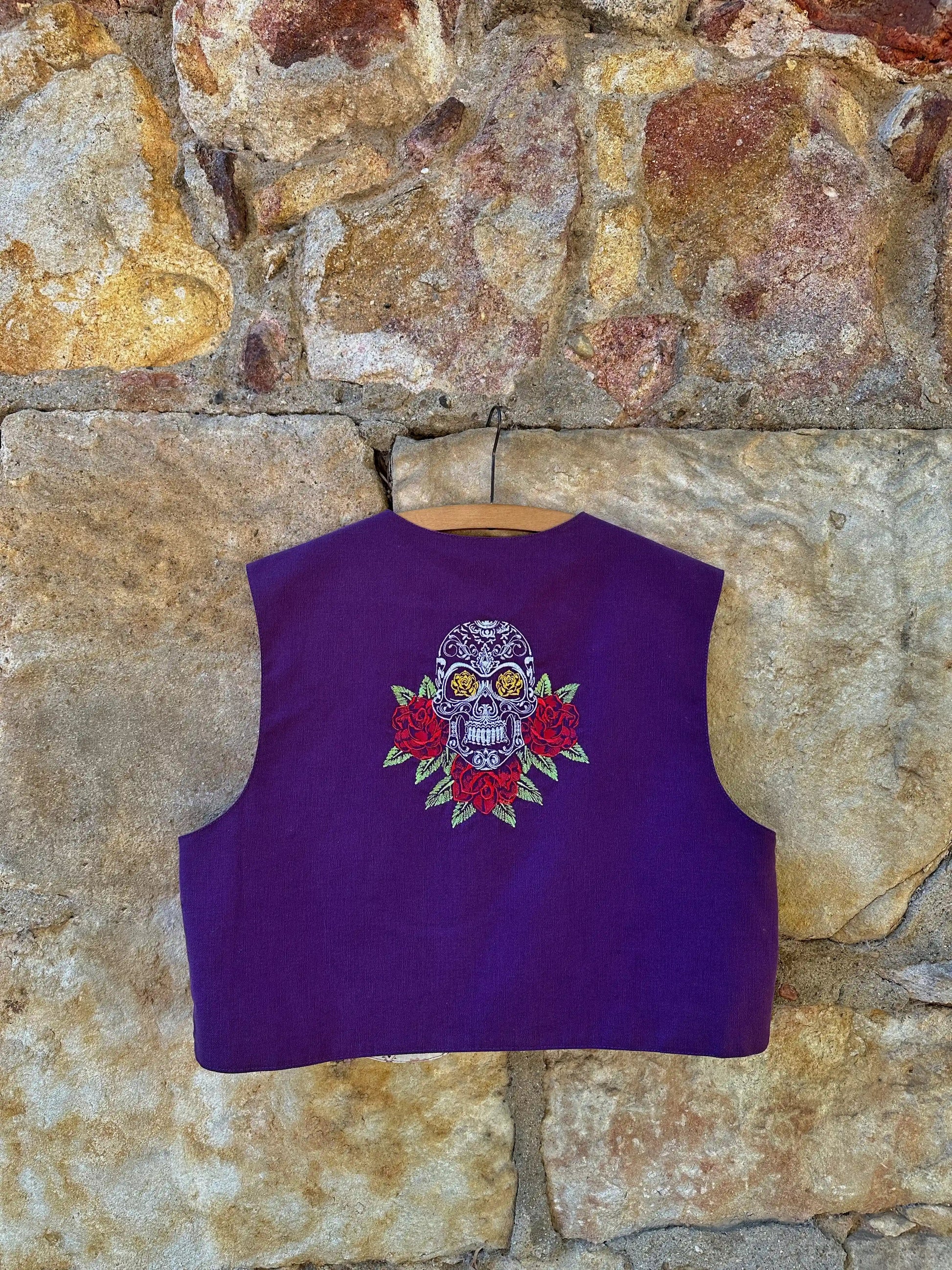 Purple vest with a skull and floral design on a stone wall background