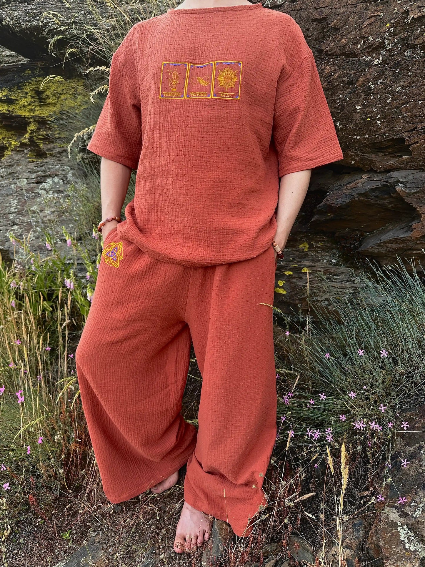 Person wearing a red outfit with embroidered designs in a natural setting