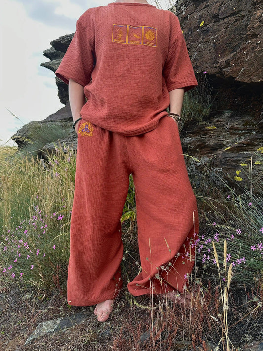 Person wearing a red outfit with embroidered designs in a natural setting