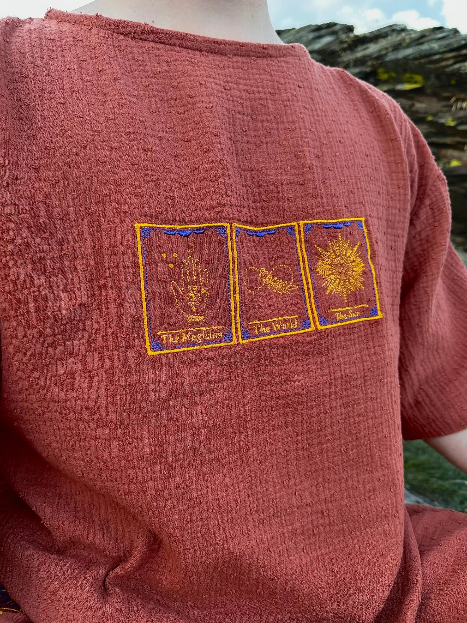 Red garment with embroidered tarot card designs on a natural background