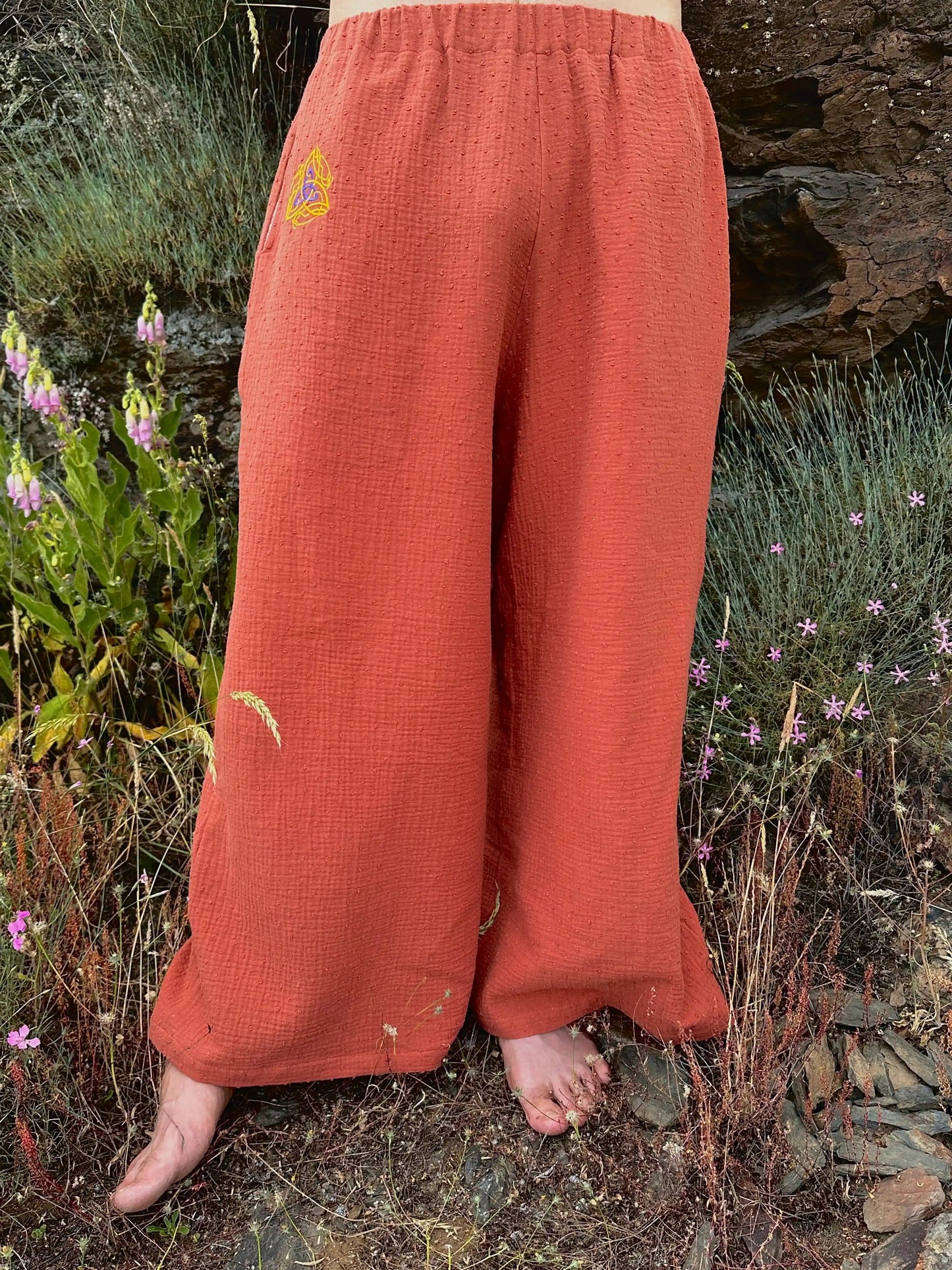 Person wearing orange pants with a logo in a natural setting
