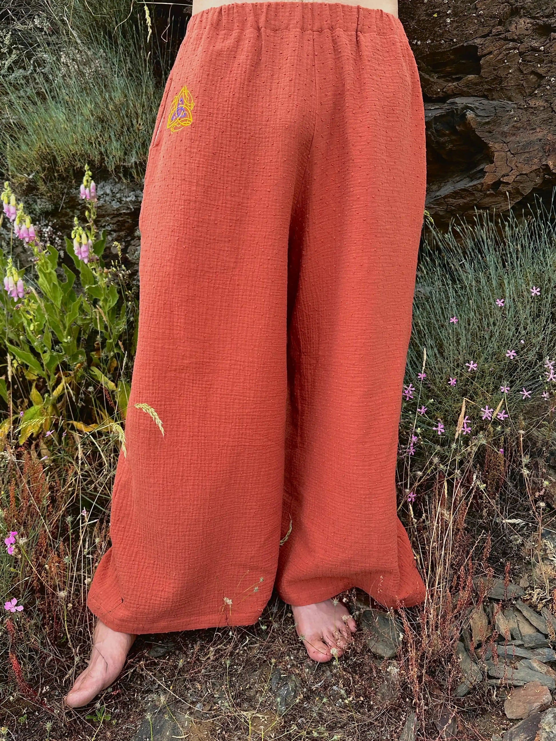 Person wearing orange pants with a logo in a natural setting