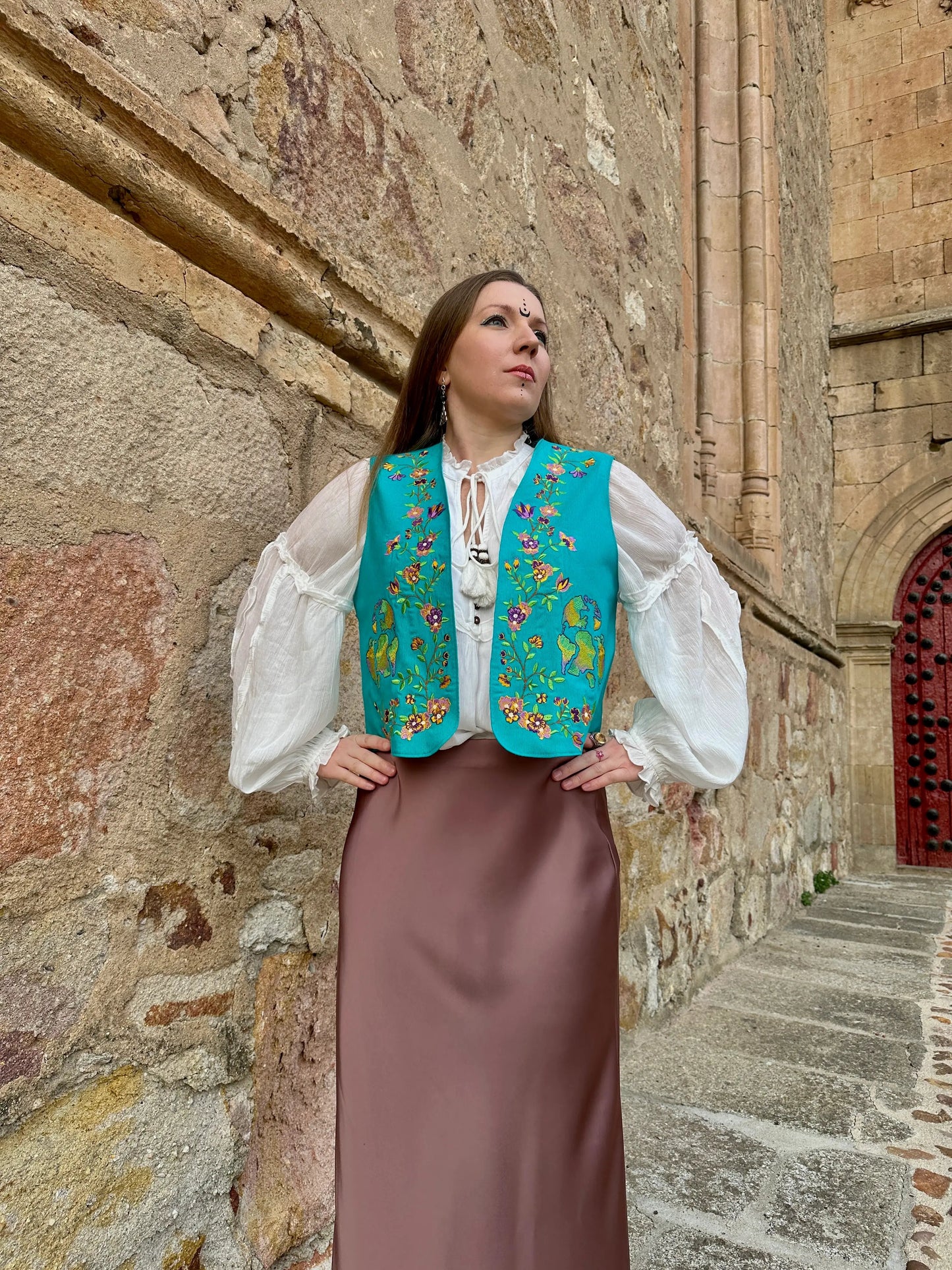 Woman in traditional attire standing against a stone wall
