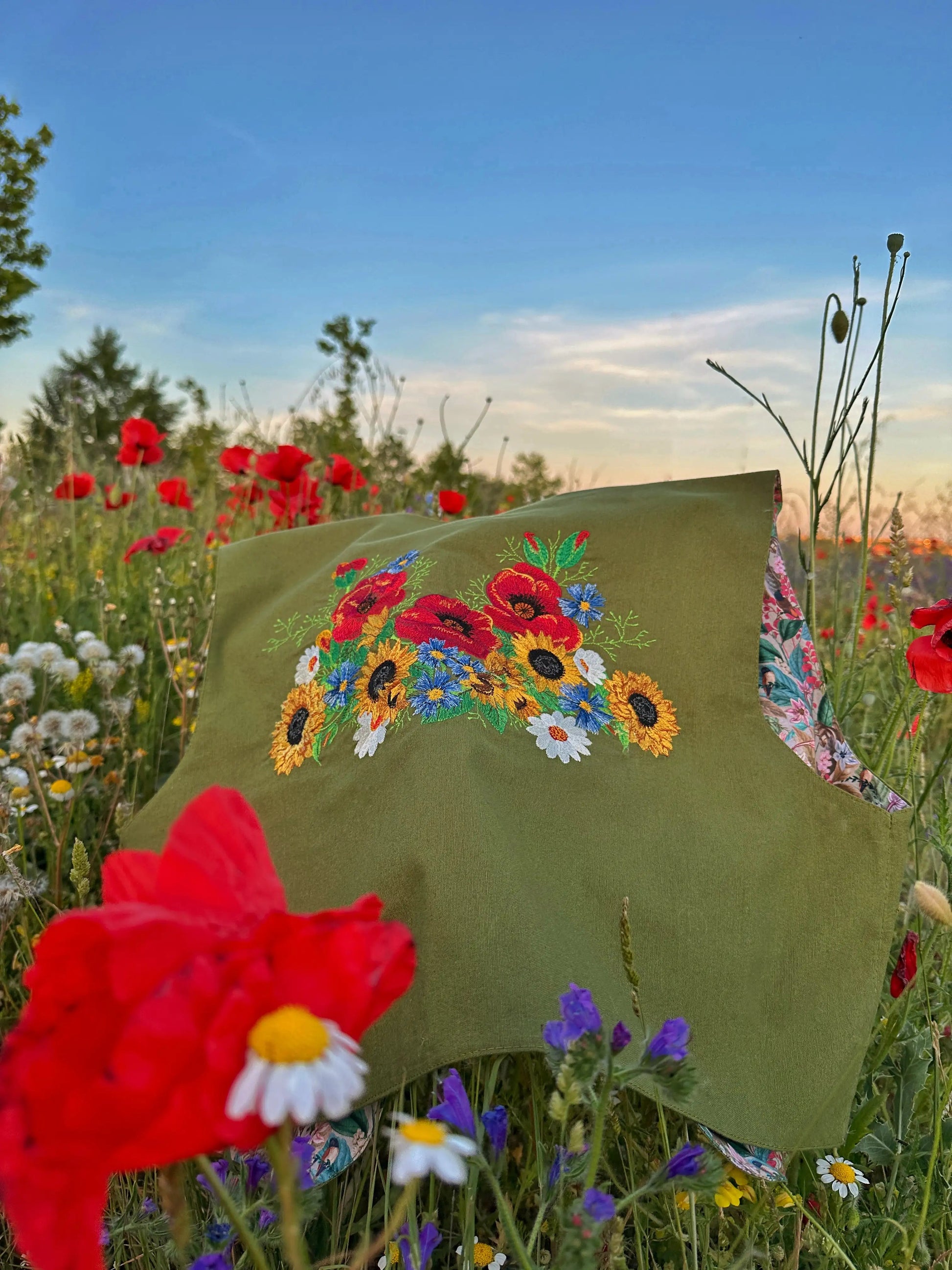 Green embroidered pillow with floral design in a field of flowers