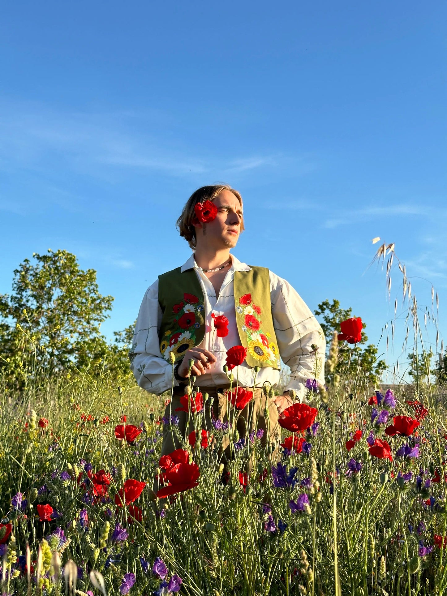 Person standing in a field of flowers with a clear blue sky