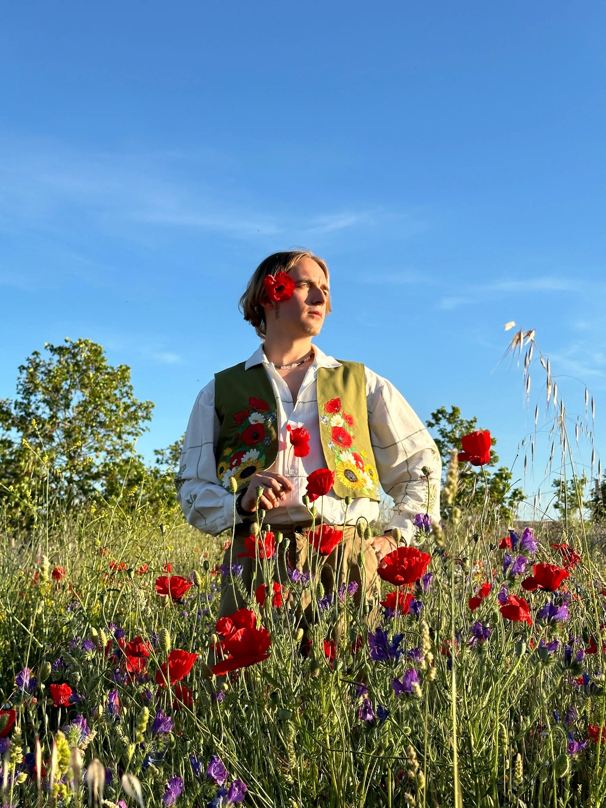 Person standing in a field of flowers with a clear blue sky