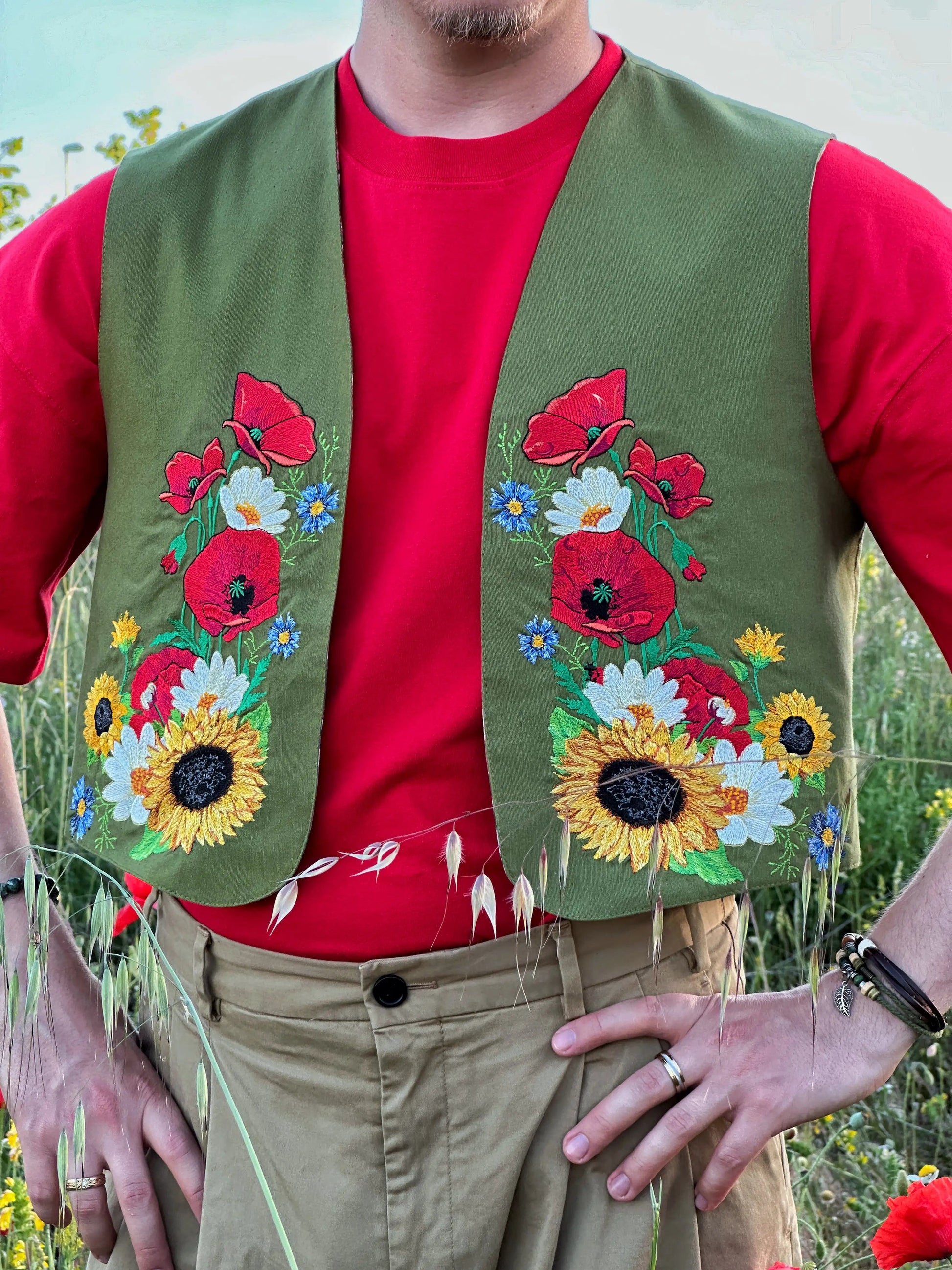 Person wearing a green embroidered vest over a red shirt in a natural setting