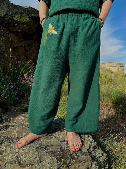 Person wearing green pants with a floral design, standing on rocks with a natural background.