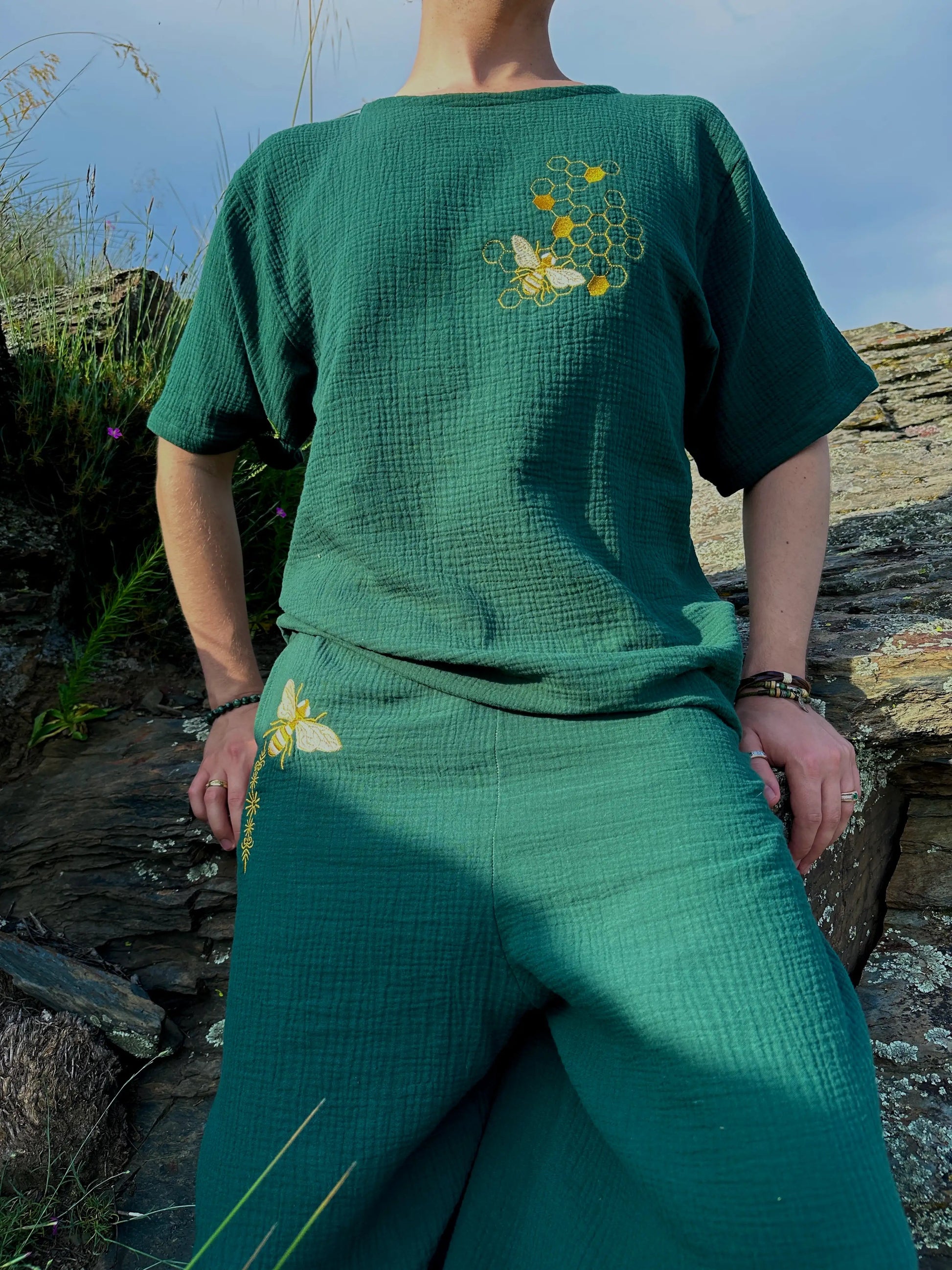 Person wearing a green outfit with floral embroidery in a natural setting