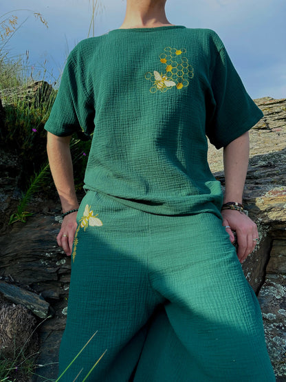 Person wearing a green outfit with floral embroidery in a natural setting