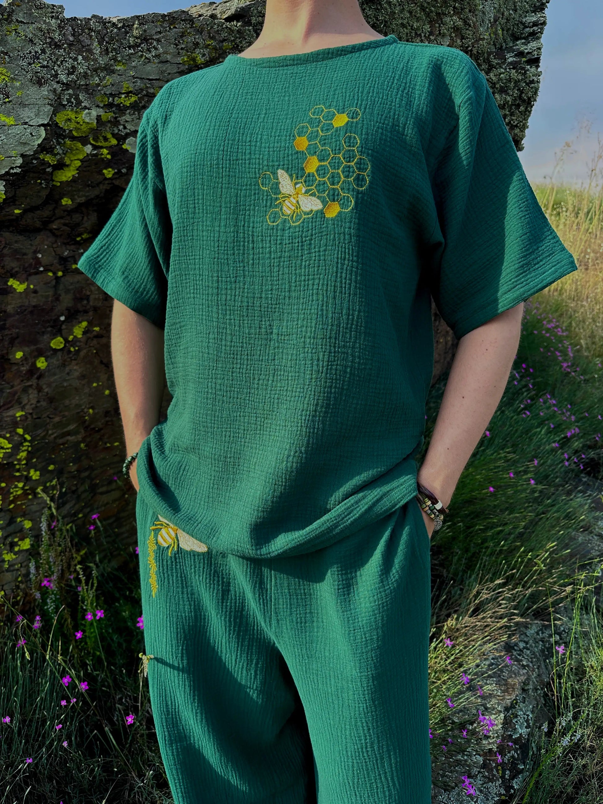 Person wearing a green outfit with embroidered designs in a natural setting