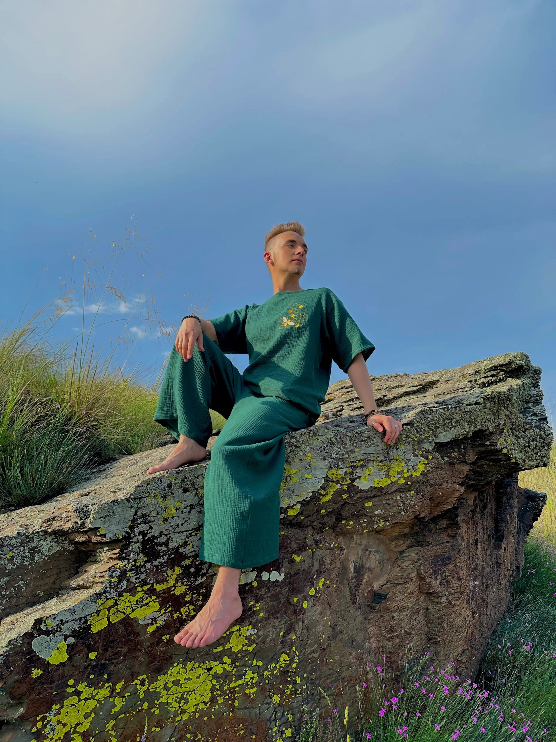 Person in green outfit sitting on a rock with a scenic background