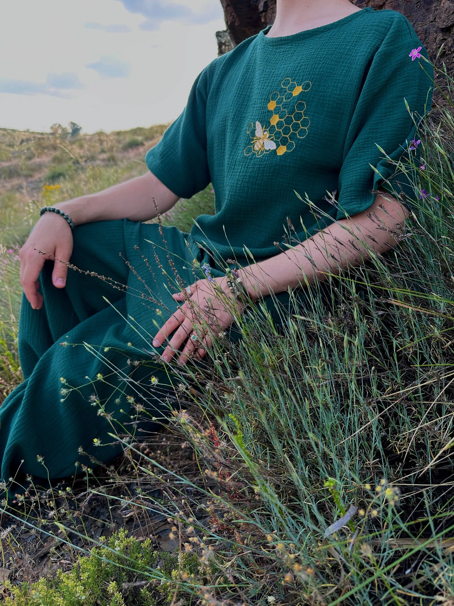 Person wearing a green outfit with a honeycomb design sitting in a natural setting.