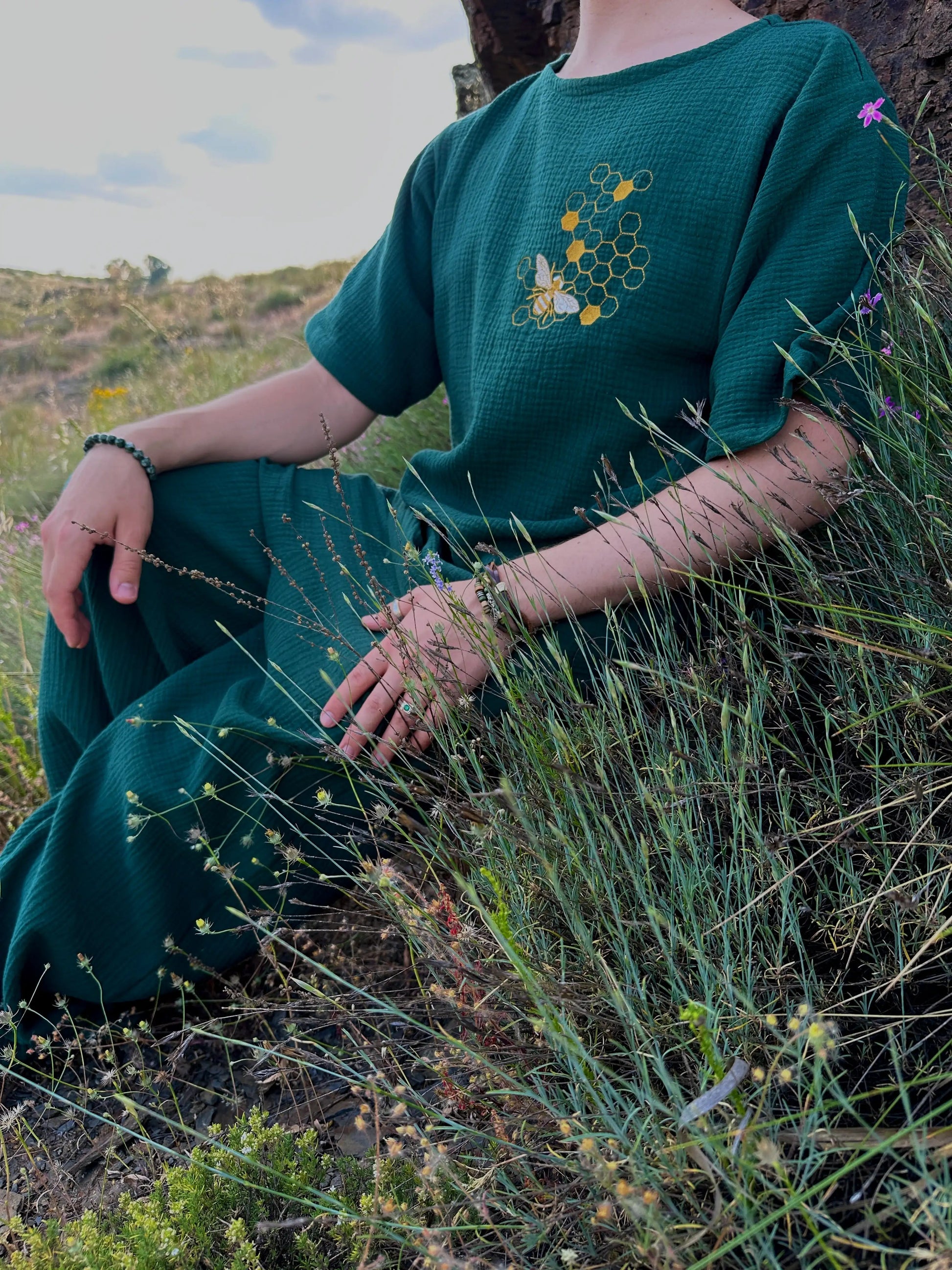 Person wearing a green outfit with a honeycomb design sitting in a natural setting.