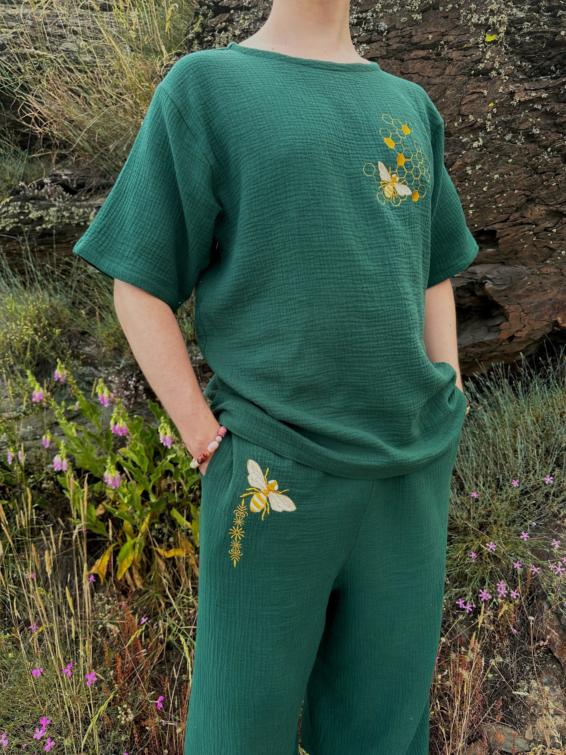 Person wearing a green outfit with floral embroidery in a natural setting