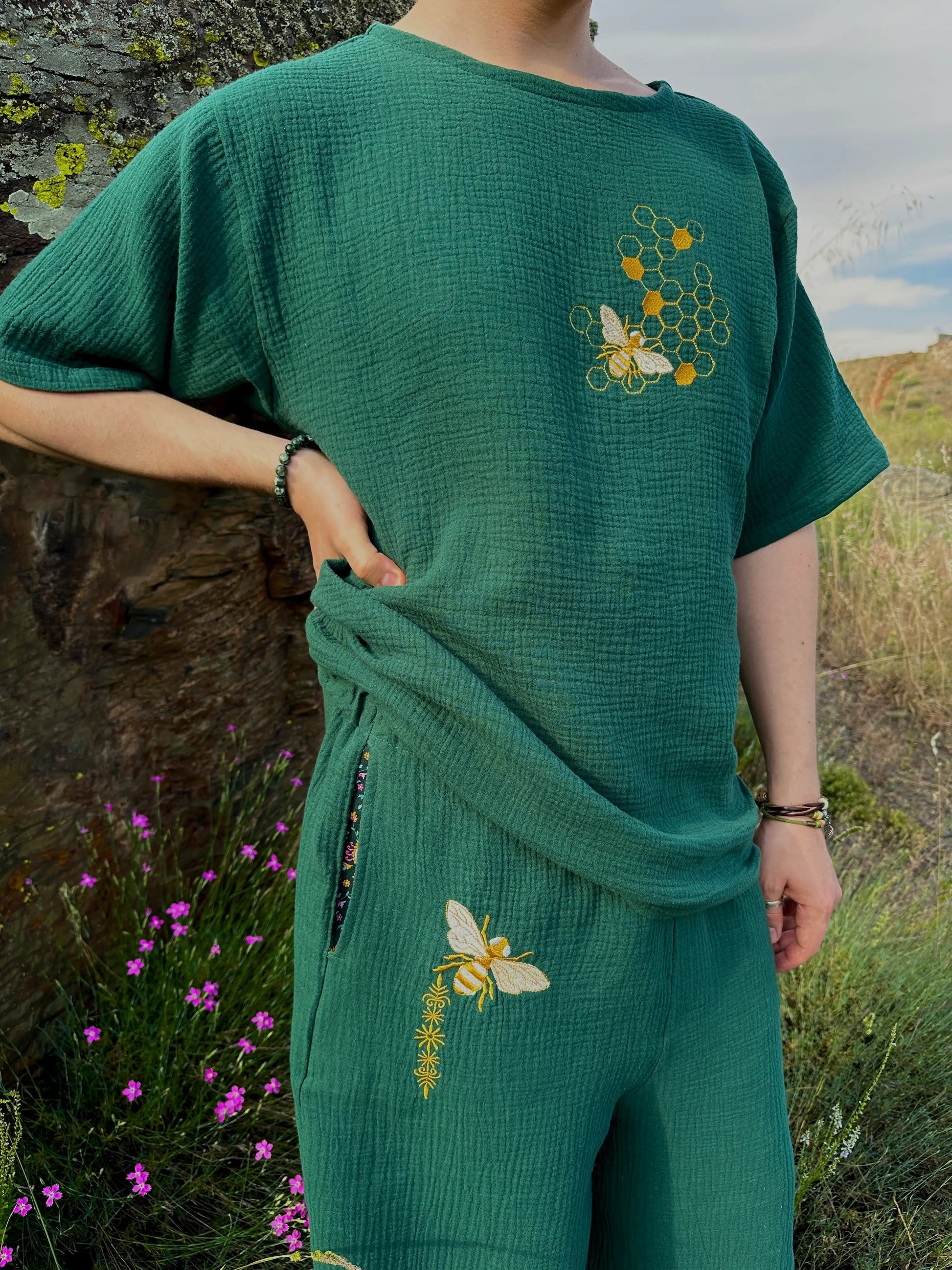 Person wearing a green outfit with embroidered designs outdoors.