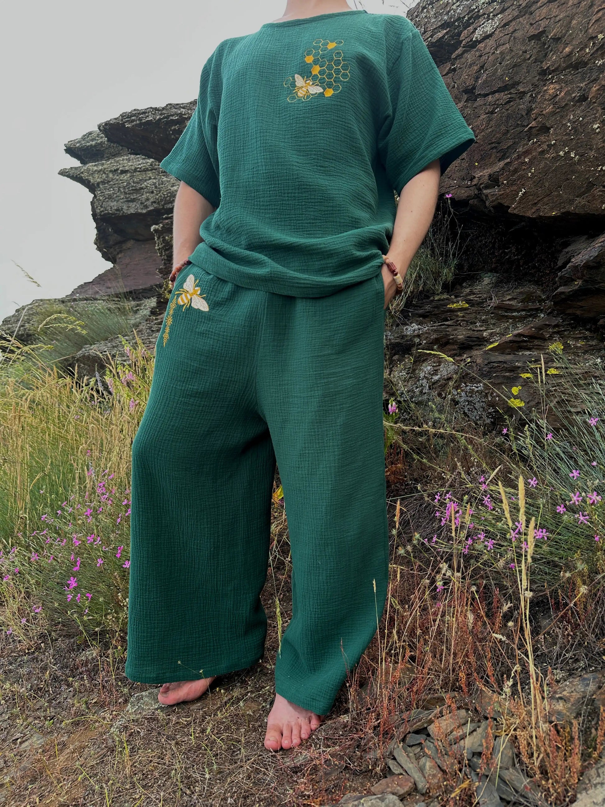 Person wearing a green outfit with nature-themed designs in a natural setting.