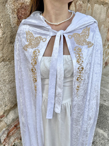 White embroidered shawl with gold butterflies worn by a person against a stone wall.