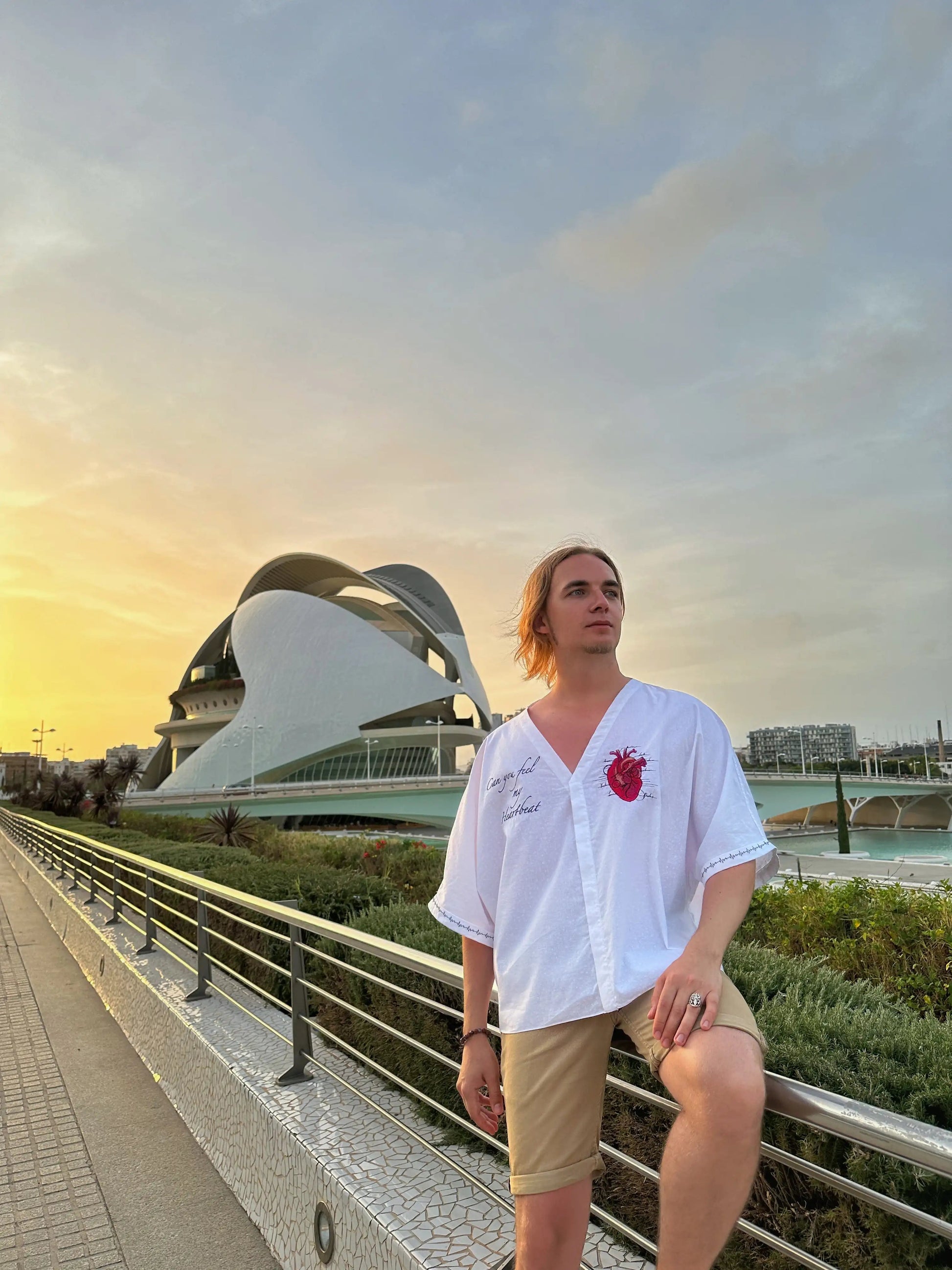 Person sitting on a bridge with modern architecture in the background