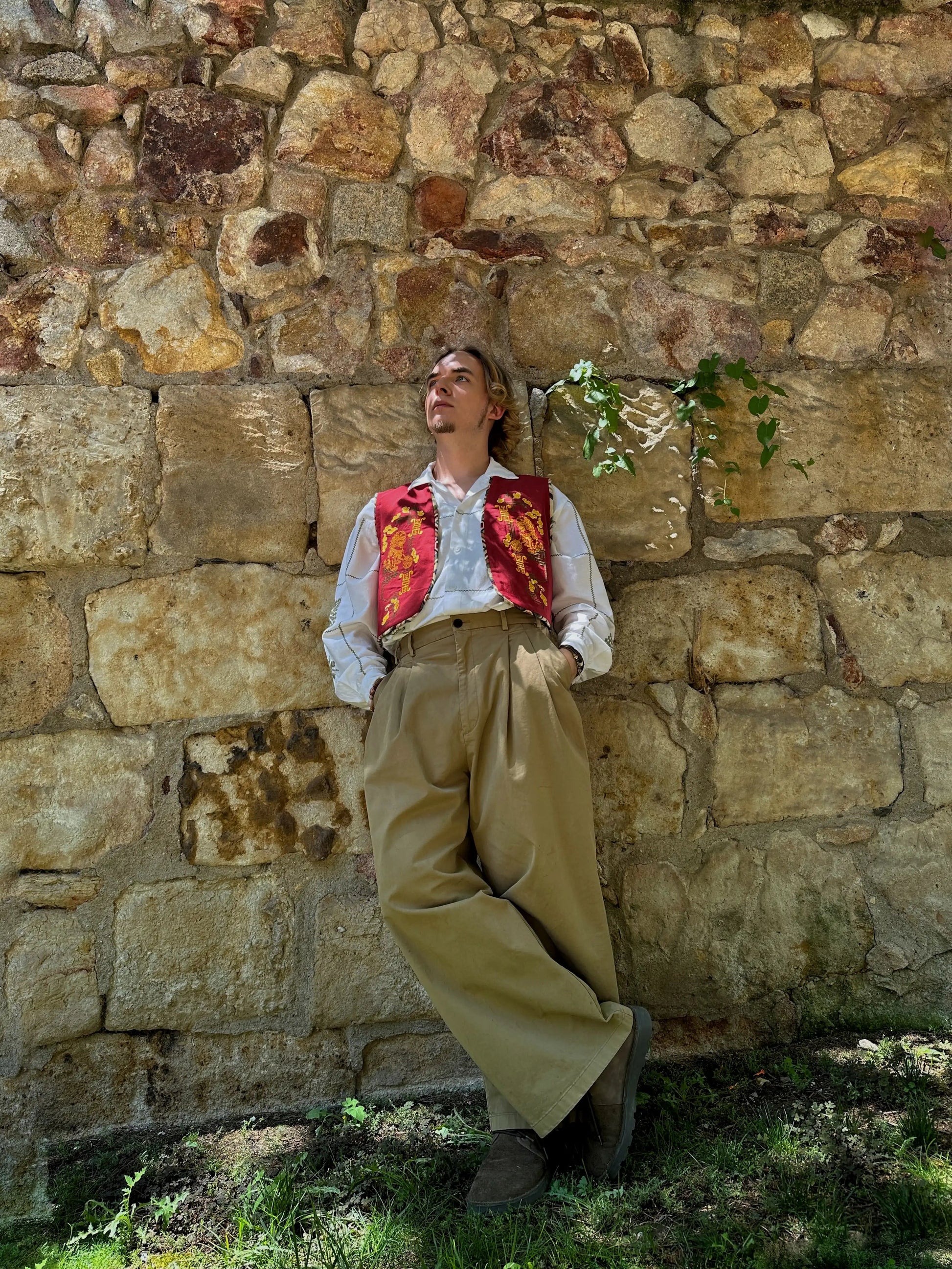 Person in historical attire leaning against a stone wall