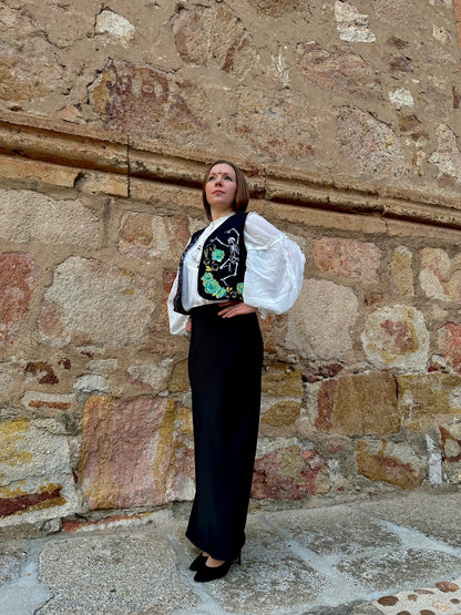Woman in a stylish outfit standing against a stone wall.