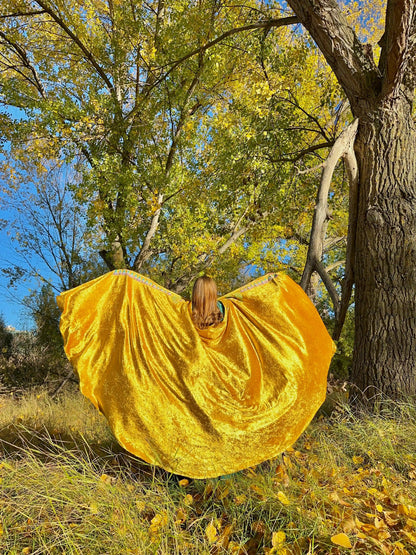 Person wearing a yellow dress standing in a natural setting with trees and grass.