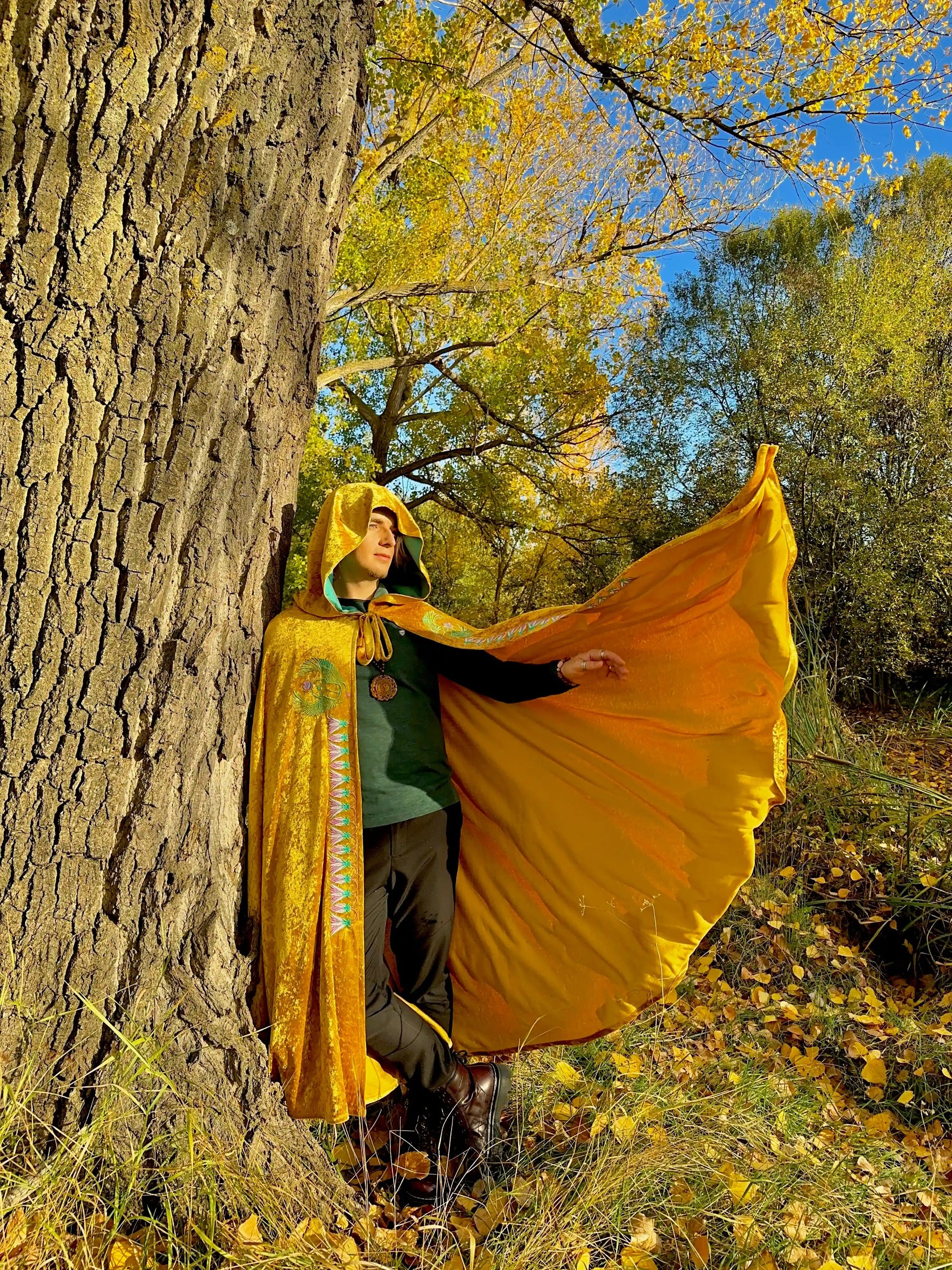 Person wearing a yellow cloak in an autumn forest