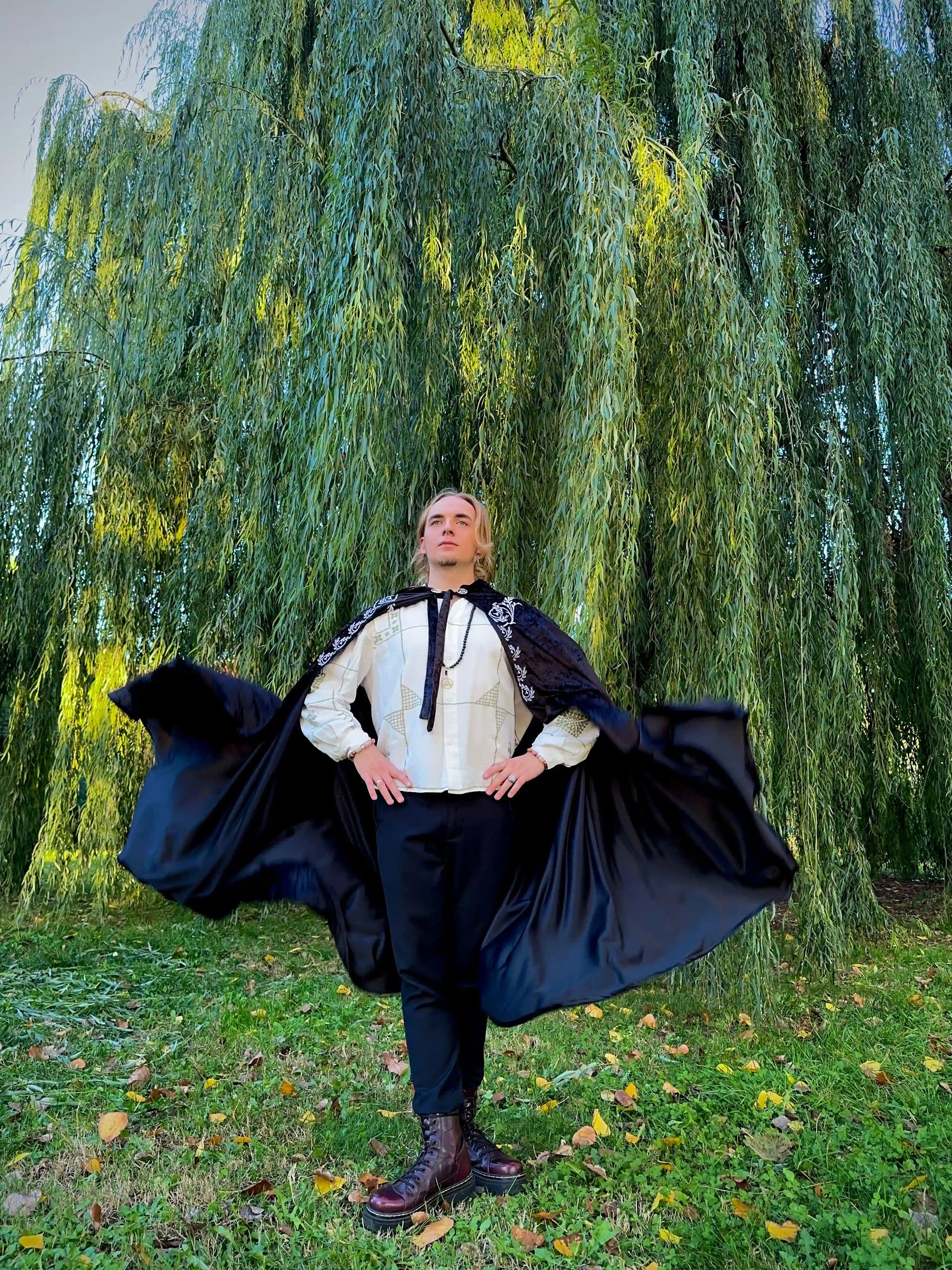 Person in a historical costume standing in front of a willow tree