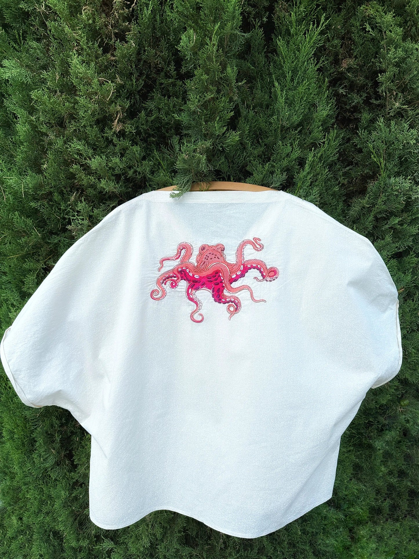 White cape with pink octopus design on a green background