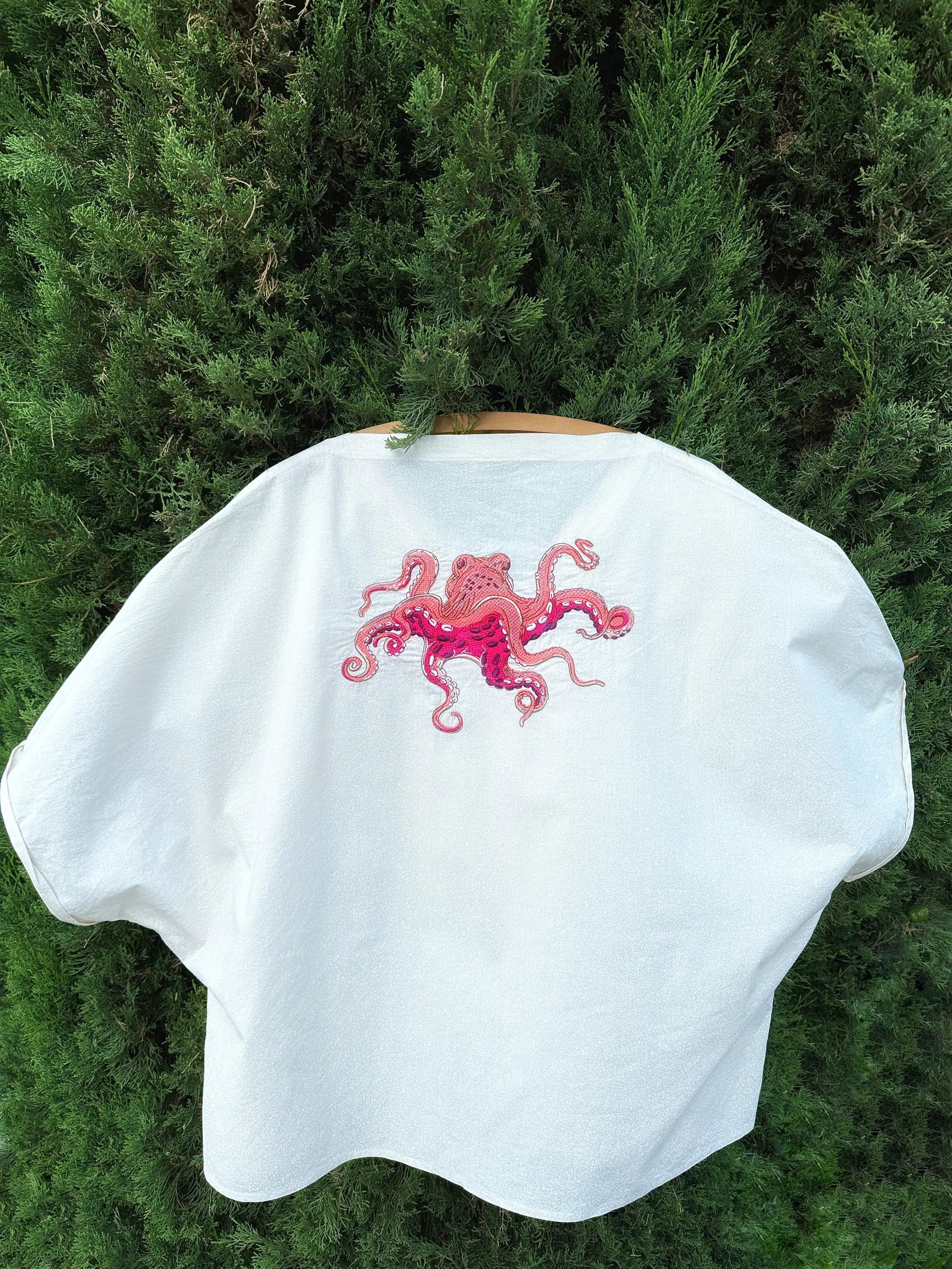 White cape with pink octopus design on a green background