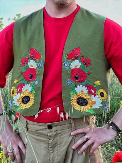 Person wearing a green embroidered vest over a red shirt in a natural setting